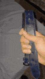 a person is holding a blue leather belt with a black buckle
