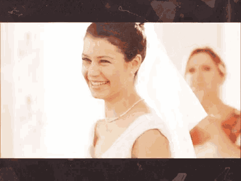 a woman in a wedding dress is smiling while standing next to a woman in a red dress .
