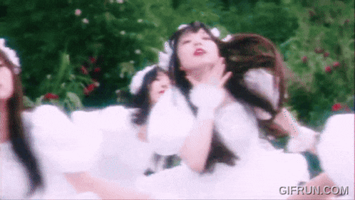 a group of women in white dresses are standing in a field .