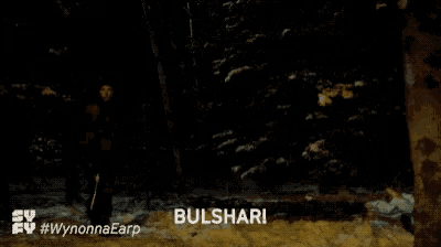 a woman is holding a gun in a dark forest and says bulshar