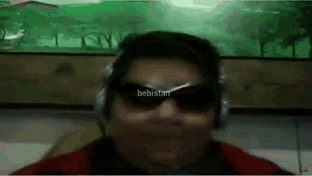 a man wearing headphones and sunglasses is making a funny face in front of a green background .