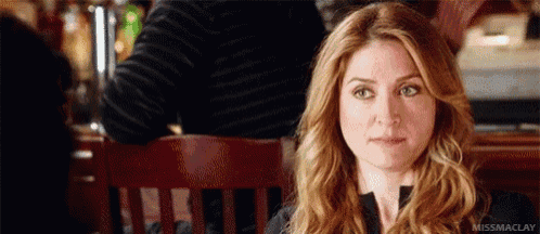 a woman is sitting at a table in a restaurant with a man behind her .