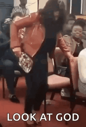 a woman is standing in front of a crowd of people in a church and holding a purse .