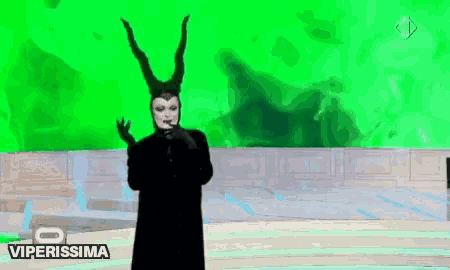 a woman in a maleficent costume is standing in front of a green background .