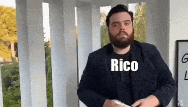 a man with a beard is wearing a black shirt with the word rico on it