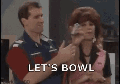 a man and a woman are standing next to each other in a bowling alley .