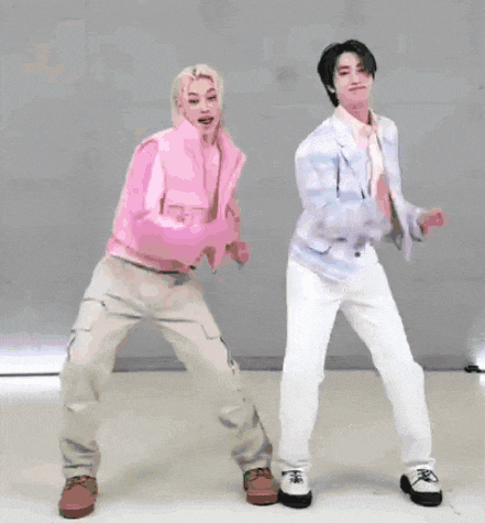 two men are dancing together in a room . one of the men is wearing a pink jacket .