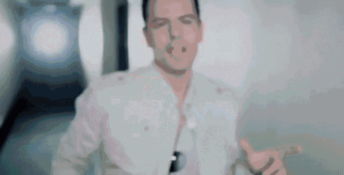 a man in a white jacket is giving a thumbs up while standing in a hallway .