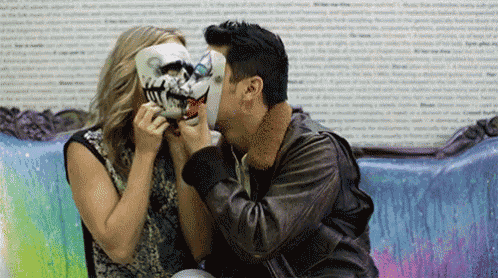 a man and a woman are kissing while wearing masks