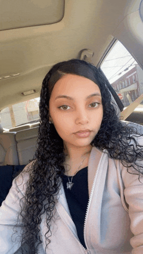 a woman with long curly hair is taking a selfie in a car