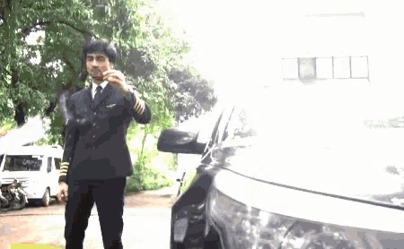 a man in a suit and tie is standing next to a black car