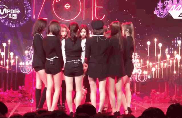 a group of girls are standing in a circle on a stage in front of a neon sign that says zolt