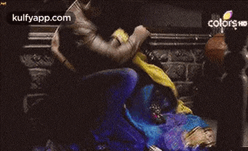 a man is kneeling down next to a woman in a blue saree .