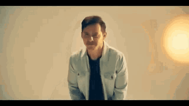 a man in a white jacket and black shirt is smiling .