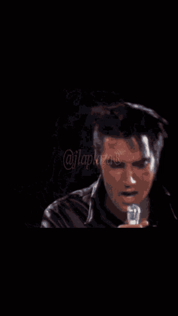 a close up of a man singing into a microphone with a blurry image of his face