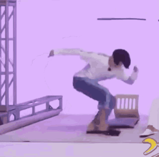a man in a white shirt and blue jeans is dancing in a room .