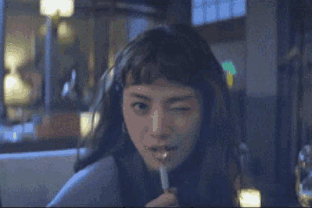 a woman is winking at the camera while holding a spoon in her mouth