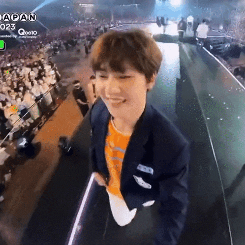a man in a suit is smiling in front of a crowd and the word japan is on the bottom