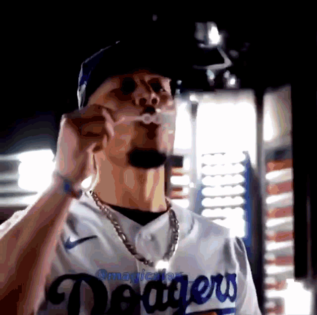 a man wearing a dodgers jersey is blowing a bubble