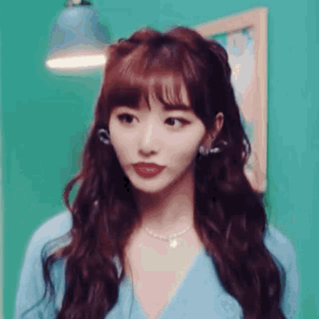 a close up of a woman with long red hair wearing a blue shirt and earrings .