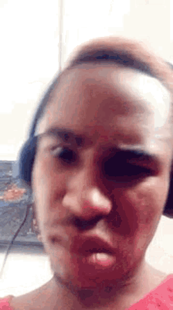 a close up of a woman wearing headphones making a funny face .
