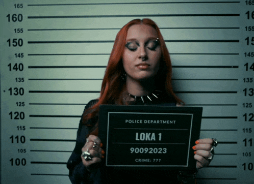 a woman with red hair is holding up a police department mug shot