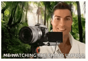 a man is holding a camera in front of a jungle background .