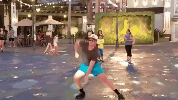 a man is dancing in a fountain in front of a group of people