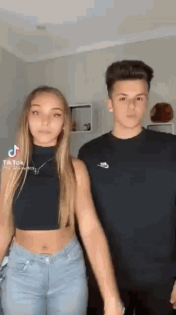a man and a woman are standing next to each other in a room holding hands .