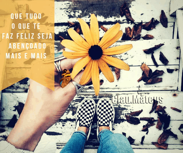 a person holding a yellow flower with the words que tudo o que te faz feliz seja abencoado mais e mais on it