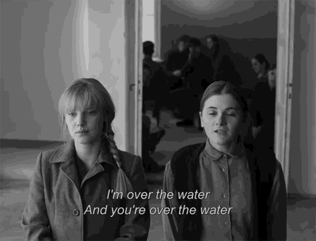 two women standing next to each other with the words i 'm over the water and you 're over the water below them