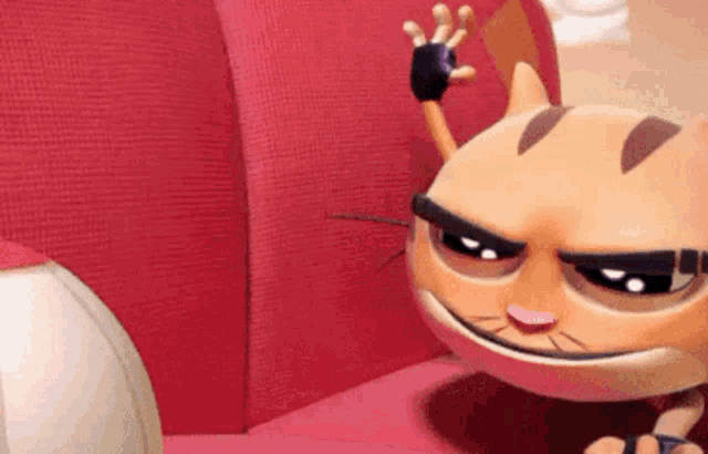 a cartoon cat is sitting on a red couch and waving .