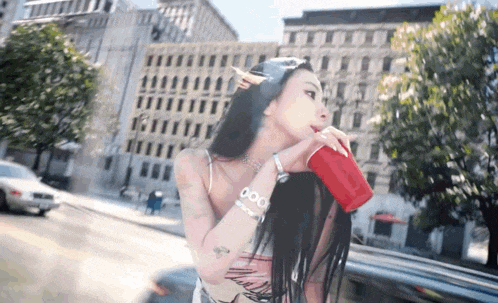 a woman drinking from a red cup that says coca cola