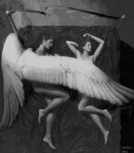a black and white photo of a man and a woman sleeping with angel wings .