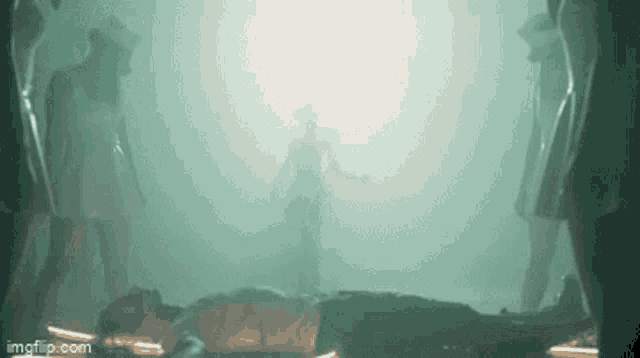 a group of people are standing around a man laying on the ground in a dark room .