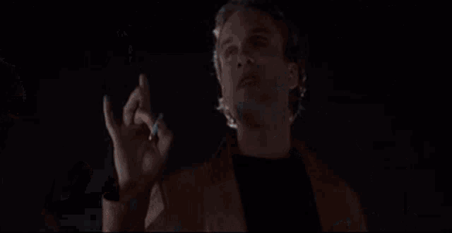 three men are standing in a dark room talking to each other .