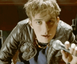a young man in a leather jacket holds a microphone in his hand