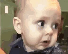 a baby is making a funny face while looking at something .
