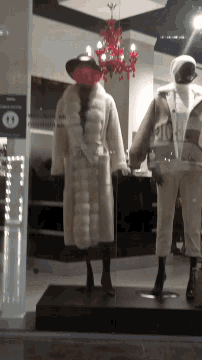 a mannequin wearing a fur coat is standing in front of a sign that says ' ao ' on it