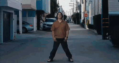 a man is standing on a street with a stop sign behind him