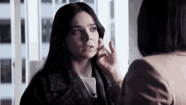 a woman is touching another woman 's face while talking to her .