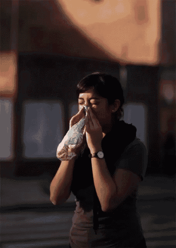 a woman wearing a watch is blowing her nose with a napkin