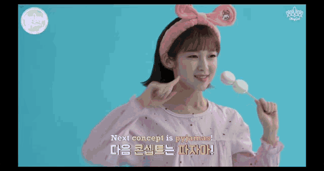 a girl wearing a pink headband is holding a marshmallow on a stick
