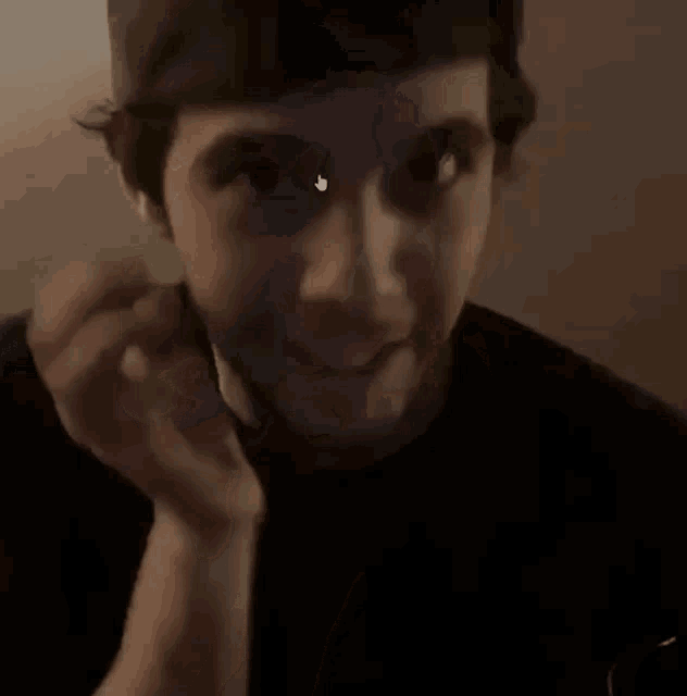 a man with a beard is holding his hand to his chin and making a face .