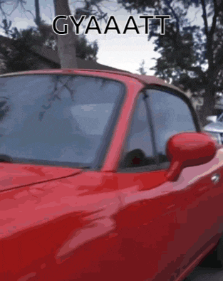 a red sports car is parked in a driveway with trees in the background and a caption that says gyaaat
