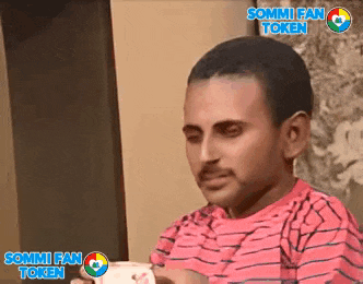 a man in a pink striped shirt is holding a cup of coffee with sommi fan token written on the bottom