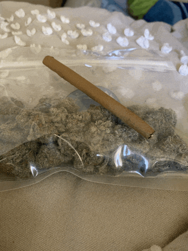 a bag of marijuana with a broken cigarette sticking out of it