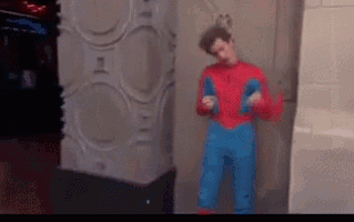 a man in a spiderman costume is standing in front of a wall