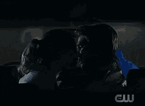 a couple kissing in a dark room with a cw logo in the background