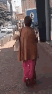 a woman in a pink skirt is walking down a sidewalk in front of a parking sign that says e